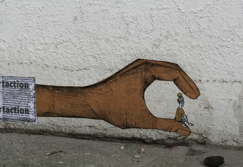 Graffiti of hand pinching a tiny girl.