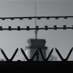 barbed wire with a prison watch tower in the background