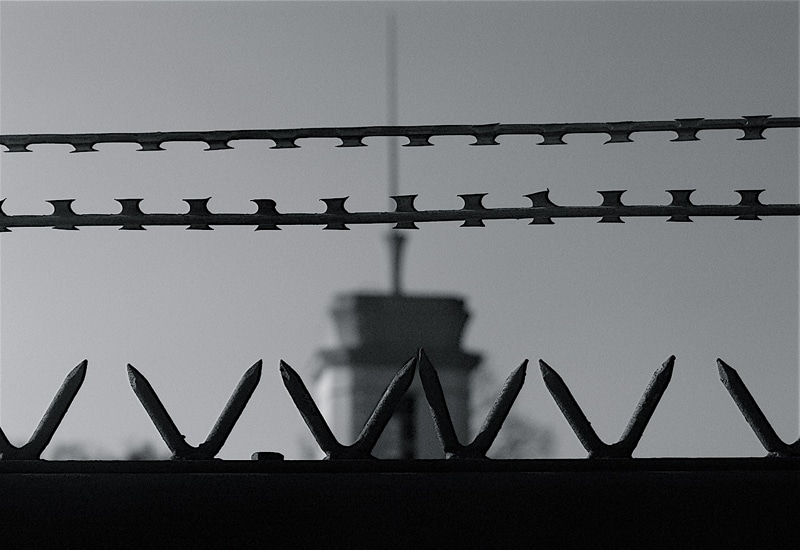 barbed wire with a prison watch tower in the background