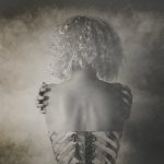 black and white photo, impressionistic, showing a girl from behind with bony shoulders, has an x-ray quality