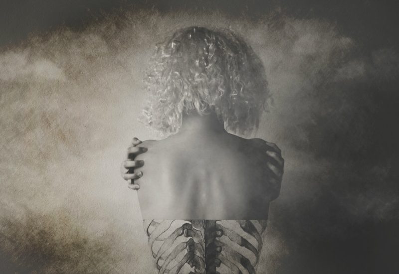 black and white photo, impressionistic, showing a girl from behind with bony shoulders, has an x-ray quality